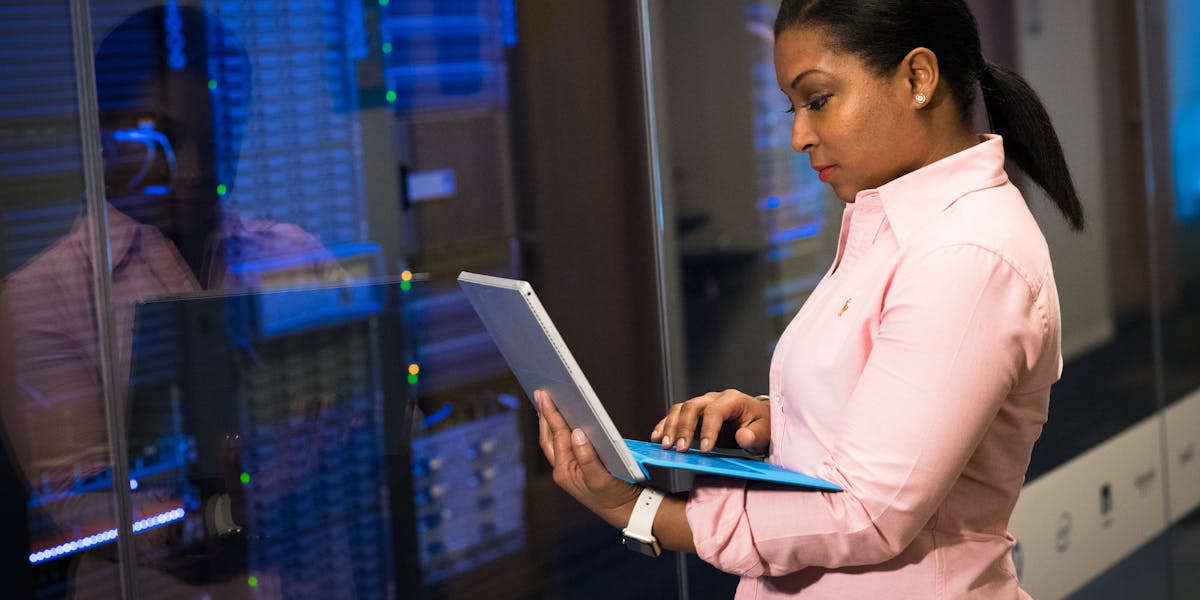 Software engineer working on a laptop in a server room environment